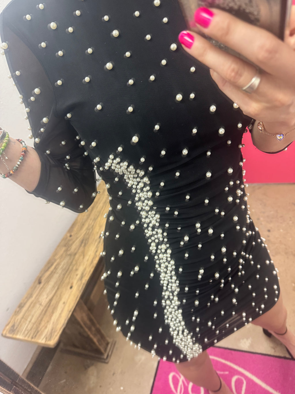 Person taking a mirror selfie wearing a black dress with white polka dots in a room with pink walls.